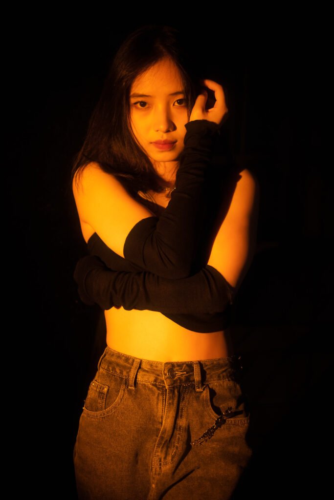 Young Asian woman posing at night in an orange light