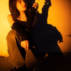 Young Chinese woman sitting in the street and smoking a cigarette portrait in a spotlight at night