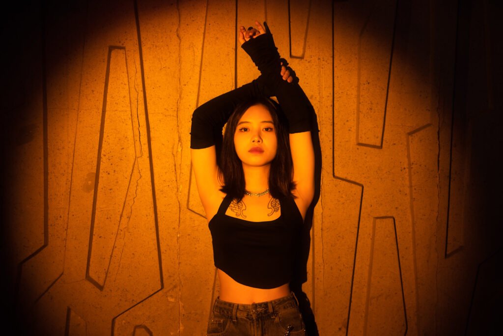 Young Asian woman posing in front of a concrete wall with geometric shapes.