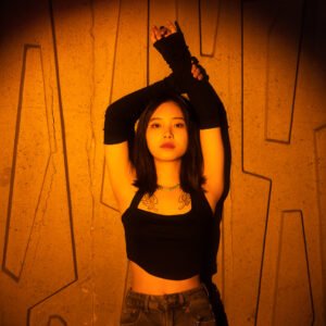 Young Asian woman posing in front of a concrete wall with geometric shapes.