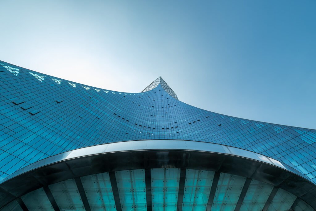 Modern curved glass building against clear blue sky