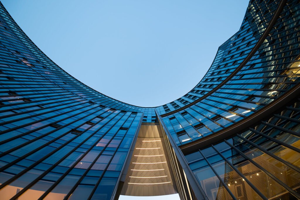 Illuminated modern curved skyscrapers against clear blue sky at dusk