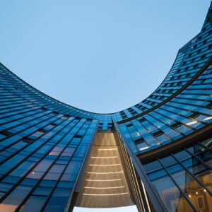 Illuminated modern curved skyscrapers against clear blue sky at dusk