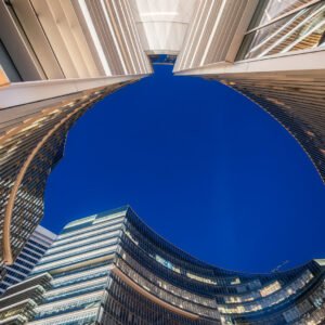 Illuminated modern curved skyscrapers against clear blue sky at dusk