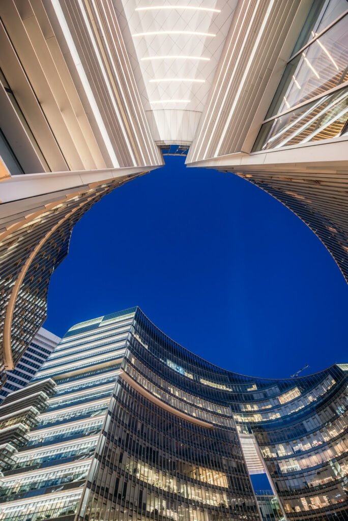 Illuminated modern curved skyscrapers against clear blue sky at dusk