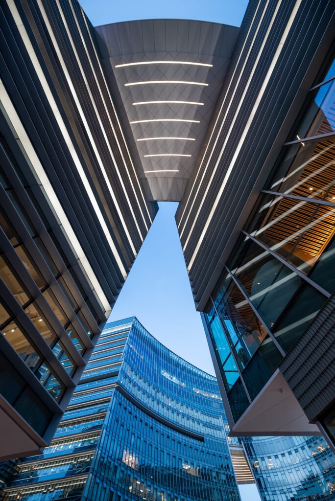 Illuminated modern curved skyscrapers against clear blue sky at dusk
