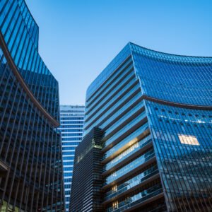 Modern curved glass skyscrapers facade reflecting clear blue sky at night