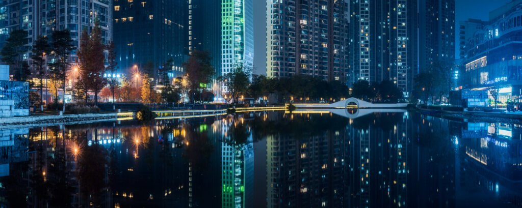 Illuminated skycrapers reflecting in a pond panorama at night