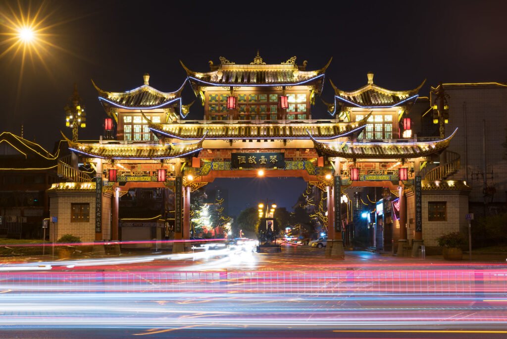 Qintailu traditional gate illminated at night with car traffic in the foreground - Chengdu