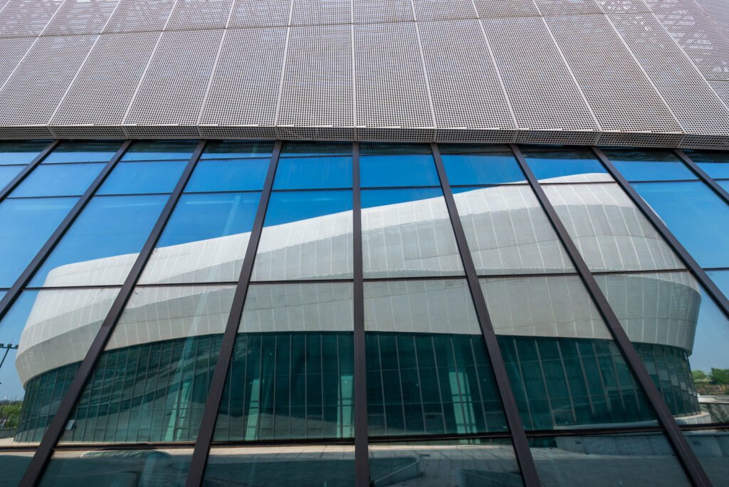 Futuristic architecture of modern building with blue reflective glass windows against clear blue sky