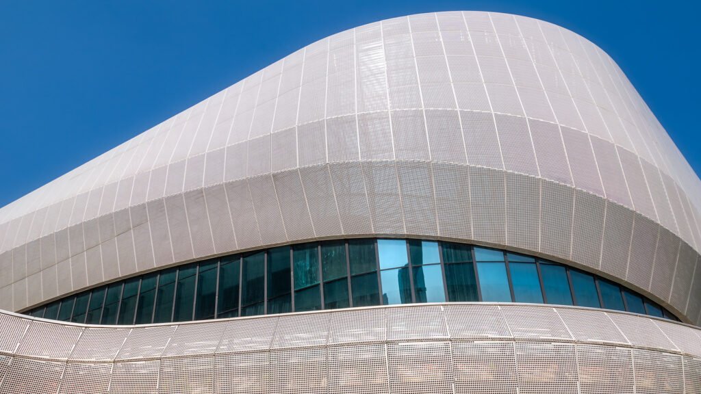 Futuristic architecture of modern building with blue reflective glass windows against clear blue sky