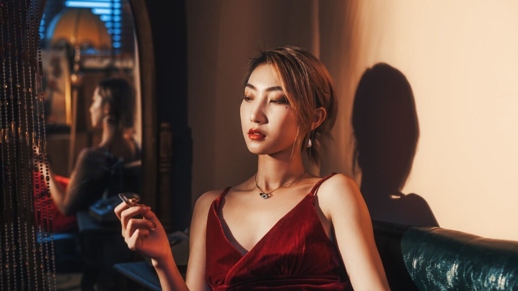 Mysterious woman in red dress smoking cigarette in dark room