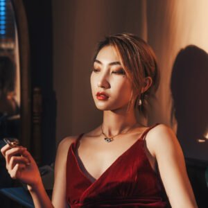 Mysterious woman in red dress smoking cigarette in dark room