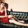 Smoking woman in red dress sitting on couch