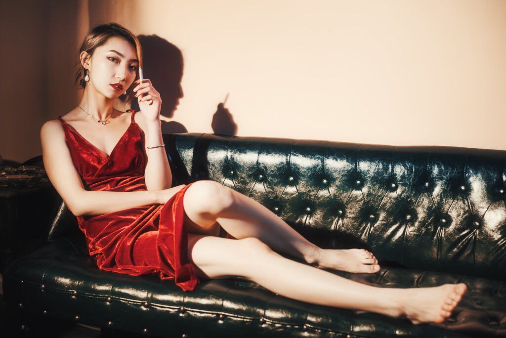 Smoking woman in red dress sitting on couch