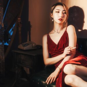 Lady in red sitting on a couch smoking.