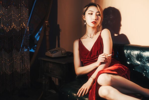 Lady in red sitting on a couch smoking.